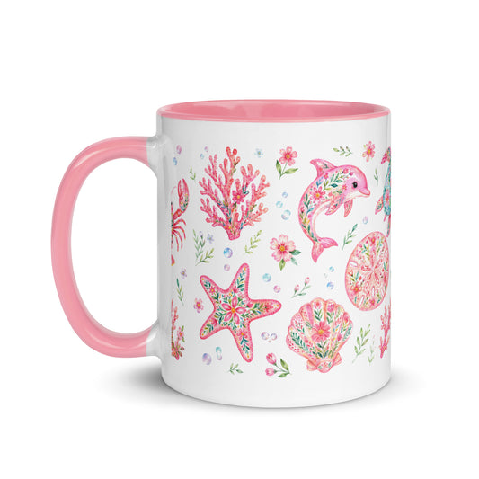 Weiße Keramiktasse mit rosa Henkel und Innenrand sowie verspieltem Muster aus Krabben, Hummern, Muscheln und Blumen.