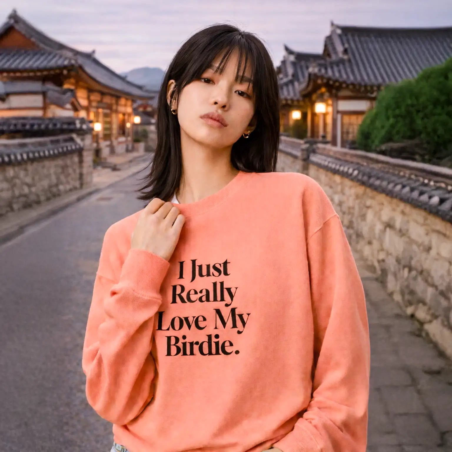 Model trägt korallenfarbenes Sweatshirt mit Aufdruck „I Just Really Love My Birdie.“