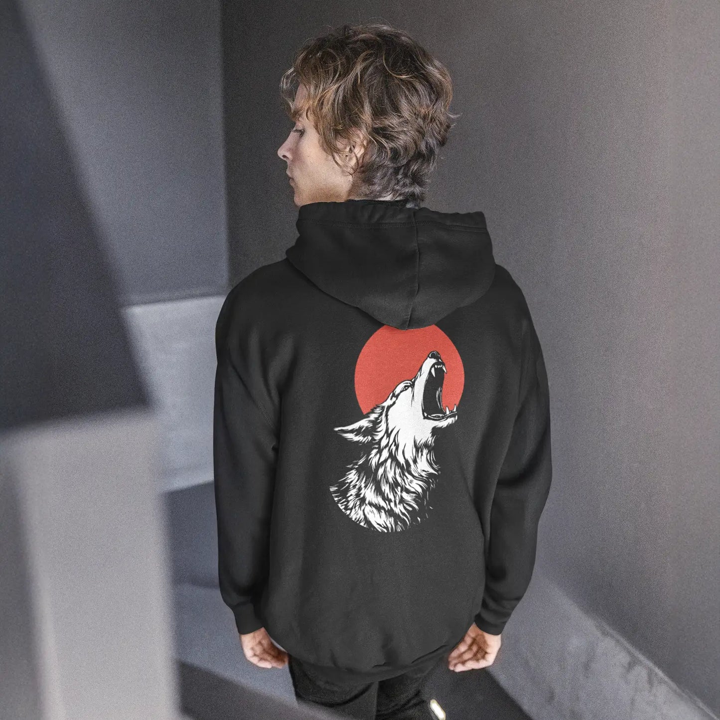 Person trägt schwarzen Hoodie mit großem Rückenprint: heulender Wolf vor roter Sonne.