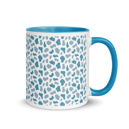 Weiße Keramiktasse mit blauem Kuhmuster sowie blauem Henkel und Innenrand.