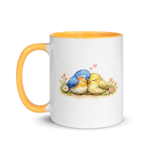 Weiße Keramiktasse mit gelbem Henkel und Innenrand sowie Illustration von zwei kuschelnden Vögeln mit kleinen Herzchen.